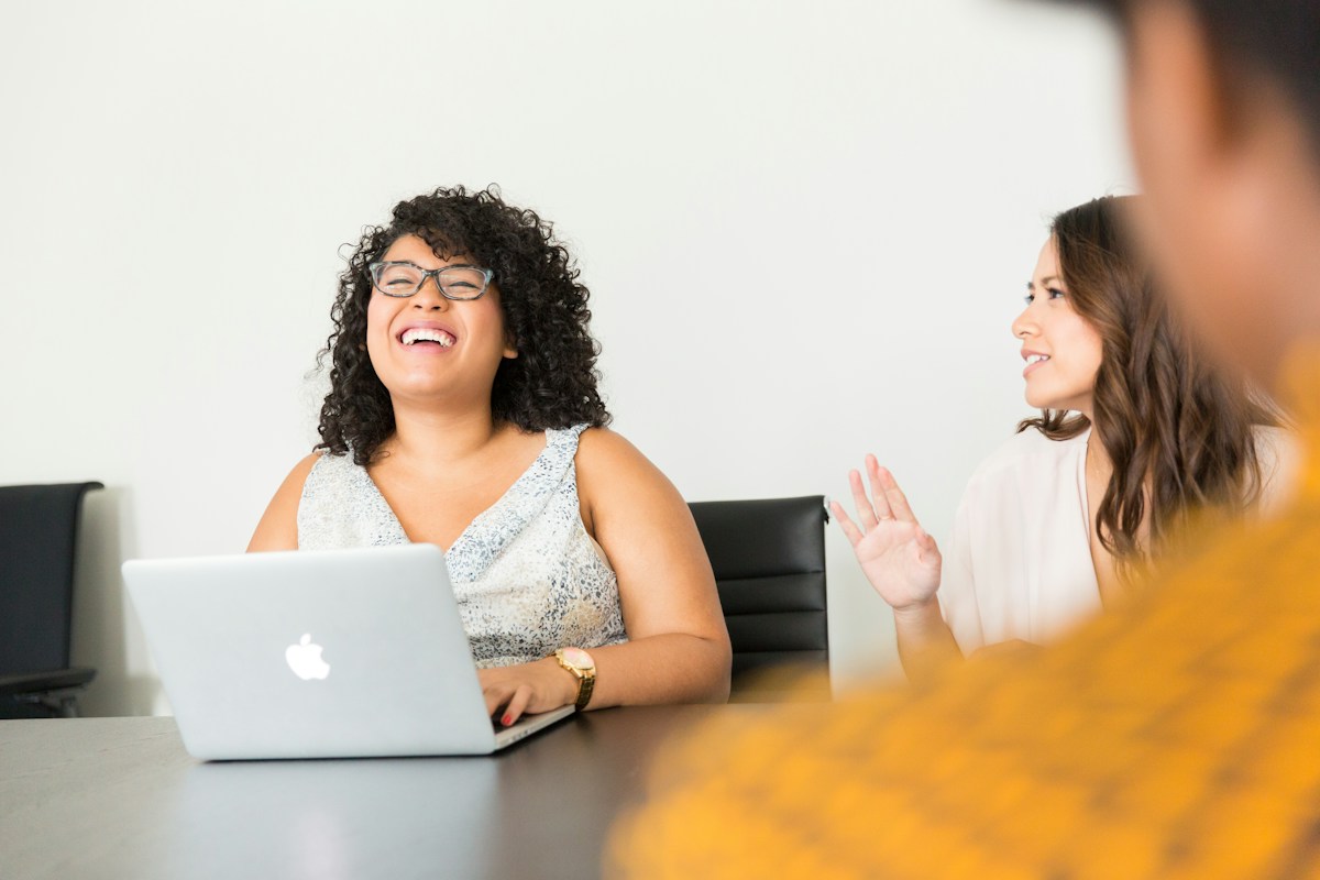 A business professional sharing a conversation with colleagues at a laptop